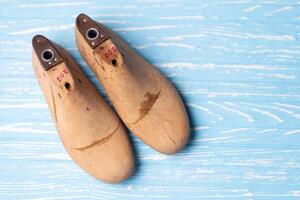 Leather samples for shoes and wooden shoe last on blue wooden table. photo