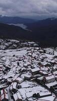 vertikal video av berg by hus täckt med snö antenn se