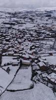 vertical vídeo de montaña pueblo casas cubierto con nieve aéreo ver video