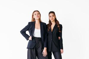 concepto de camaradería en negocio. dos joven mujer de negocios vestido negro formal traje en pie estudio aislado blanco antecedentes. foto