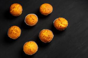 Appetizing muffins stand on a table top view. Traditional pastries on a dark background minimalism. photo