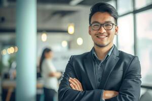 ai generado confidente asiático hombre en traje y lentes con brazos cruzado en moderno corporativo oficina foto