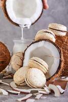 Coconut macarons with chocolate and coconut flakes on a table with a coconut in the background photo