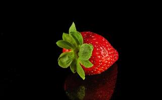 Strawberry rest on a black surface, a vibrant product from nature's bounty photo