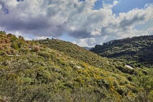 un sereno imagen de verde colinas y un azul cielo con mullido blanco nubes vibrante colores y lozano vegetación cubrir el sierras. Perfecto para antecedentes o viaje folletos foto