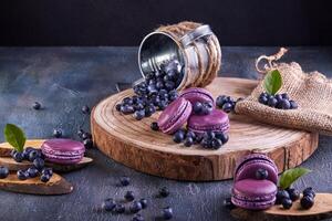 A wooden cutting board showcasing a vibrant display of purple macarons and blueberries, highlighting the natural foods and colorful ingredients used in creative culinary art photo