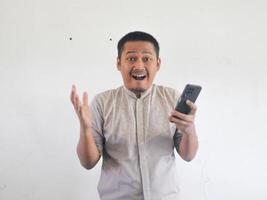asiático hombre participación su móvil teléfono con grave expresión foto