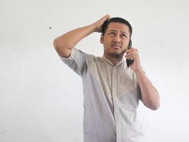 Asian man holding his mobile phone with serious expression photo