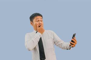 adulto asiático hombre conmocionado cara mientras mirando a móvil teléfono foto