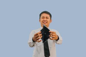 Adult Asian man showing empty wallet with shocked and sad face expression photo