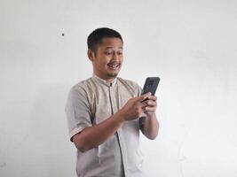 Adult Asian man looking  his mobile phone with surprised expression photo