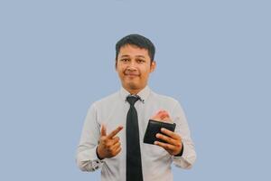 Adult Asian man smiling confident while pointing to wallet full of money that he hold photo