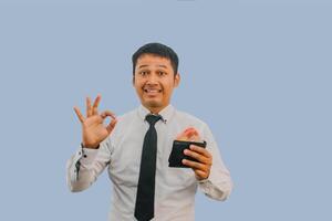 Adult Asian man smiling while holding wallet with money and give OK finger sign photo