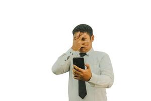 Adult Asian man showing scare and shocked expression when looking to his mobile phone photo