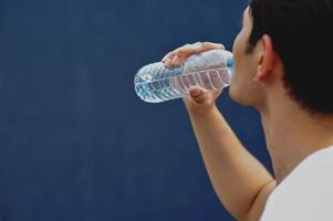 Drink water from a clean water bottle, quench your thirst with water. Man drinking water for good health photo