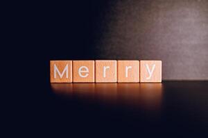 Wooden blocks form the text Merry against a black background. photo