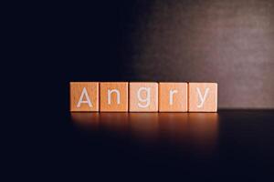 Wooden blocks form the text Angry against a black background. photo