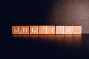 Wooden blocks form the text Mournful against a black background. photo