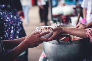 Hands of poor people asking for food from volunteers helping concept of food donation photo