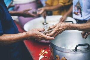 Hands of poor people asking for food from volunteers helping concept of food donation photo