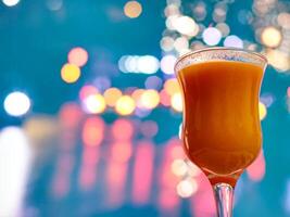 naranja jugo en bar vaso en frente de borroso parpadeo luces antecedentes foto