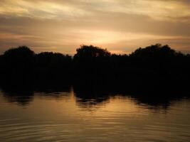 Colorful Sunset with tree silhouette reflecting at the lake photo