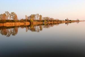 lago casa en otoño reflejando en tranquilo río foto