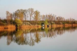 Lake House in Autumn Reflecting in Tranquil River photo