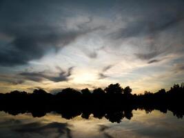 Blue and yellow sunset sky with clouds reflecting at the lake photo