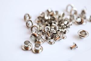 Metal silver eyelets on white table with bokeh blur in bright day light photo