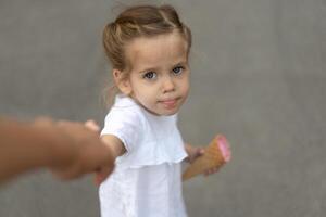 Little caucasian girl 3 years old eats ice cream closeup portrait photo