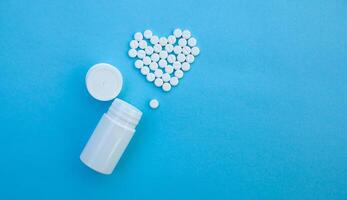 medicine, healthcare and pharmacy concept - pills and of drugs in shape of the heart photo