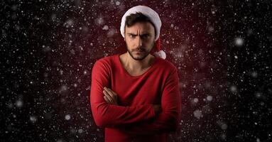 Young serious handsome caucasian guy in red sweater and Santa hats stands on red background in studio and feel angry photo