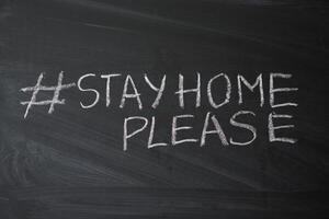 Hashtag stay at home. Outbreak Warning. written white chalk on blackboard in connection with epidemic of coronavirus worldwide. photo