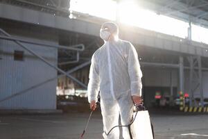hombre vestido blanco protector mono pulverización superficie antibacteriano desinfectante rociador durante cuarentena foto