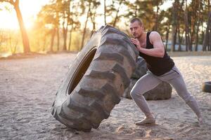 Strong man training workout lifting large tire outdoor DIY gym. photo