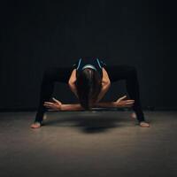 Woman practicing yoga against a dark texturized wall photo