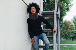 joven afro americano joven empresario o estudiante vistiendo negro suéter tipo con cuello de tortuga suéter y bufanda y teniendo Rizado oscuro cabello. concepto de elegante y de moda Mira foto