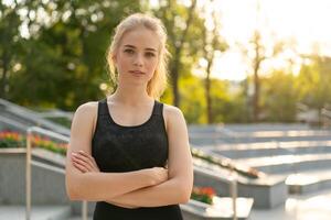 deporte y aptitud física. joven caucásico mujer vestido ropa de deporte en pie al aire libre verano parque luz de sol antecedentes foto