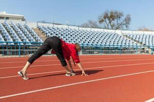 young fitness woman runner warm up before running on track photo