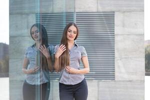 negocio mujer 35 años vestido raya camisa con largo pelo en pie cerca oficina edificio al aire libre foto