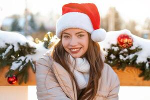 Winter portrait young adult beautiful woman in Santa hat. Christmas mood. Snowing. Winter beauty fashion concept photo