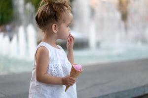 Little caucasian girl 3 years old eats ice cream closeup portrait photo