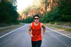 Caucasian middle age man athlete runs sunny summer day on asphalt road in the forest. photo