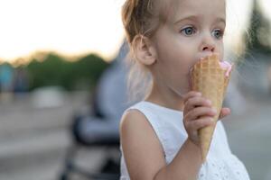 Little caucasian girl 3 years old eats ice cream closeup portrait photo