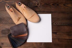 Leather samples for shoes and wooden shoe last on blue wooden table. photo