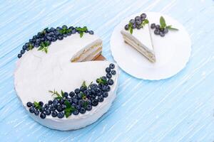 Appetizing cheesecake cake biscuit pillow decorated white cream blueberries and mint stands on wooden blue rustic table photo