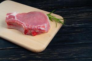 Top view of one pieces raw pork chop steaks with rosemary on a cutting board. photo