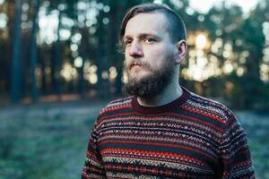 Portrait brutal bearded hipster man in the forest photo