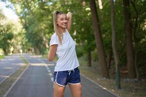 mujer corredor extensión brazos antes de hacer ejercicio verano parque Mañana foto